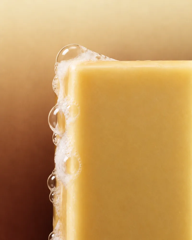 Verse 002 Silken Gold: the edge of a golden bar, close up, with a line of lather along it.